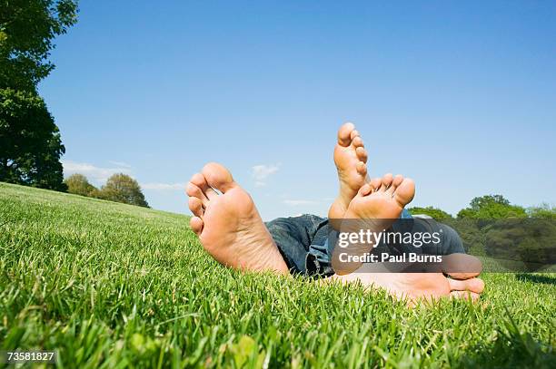 young couple lying in grassy park, close-up of bare feet - mens bare feet stockfoto's en -beelden