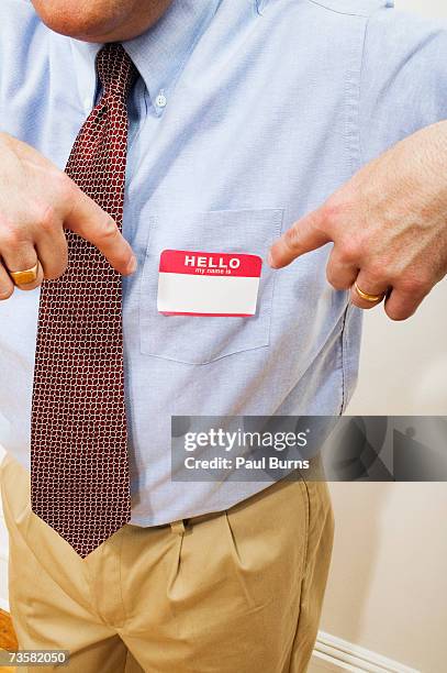 male office worker pointing to name tag on shirt - nameplate stock-fotos und bilder