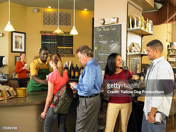 young waiter at counter serving customers, including teenager (14-15), in queue in cafe - customers lining up stock pictures, royalty-free photos & images