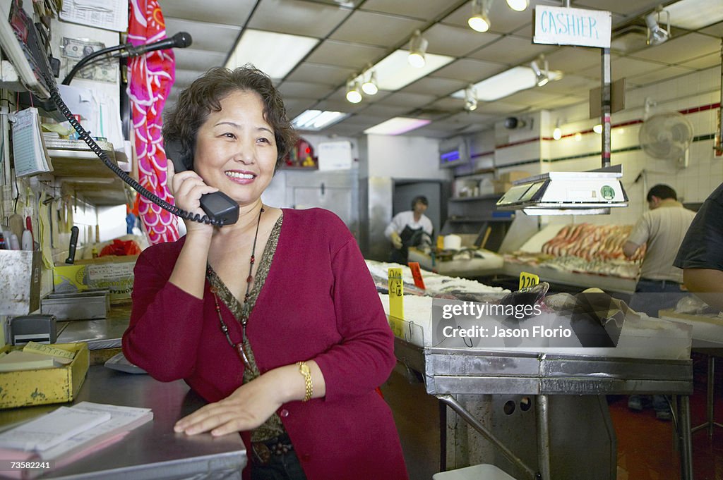 Woman on the phone at fish market, smiling