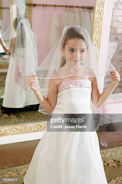 girl (7-8) in bridal shop holding veil, portrait - jason florio stockfoto's en -beelden