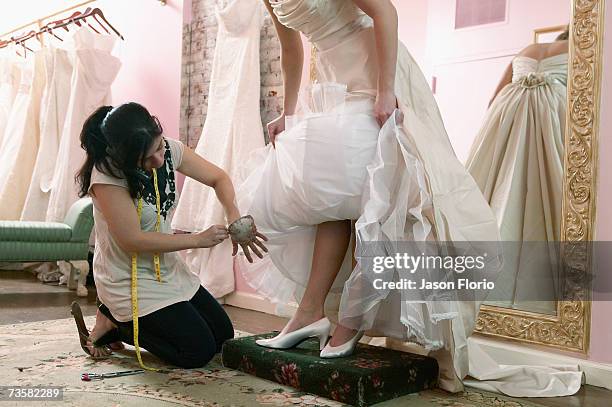 tailor adjusting hem of wedding dress - jason florio stockfoto's en -beelden
