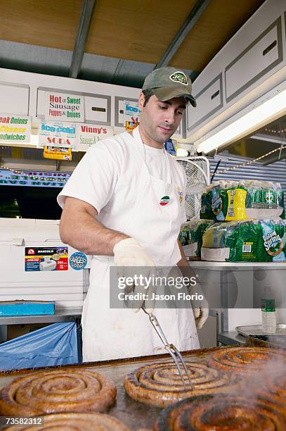 man cooking sausage on hot plate - jason florio stockfoto's en -beelden