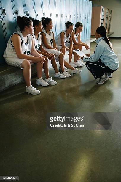 coach speaking to female basketball team in locker room - teenage girl basketball photos et images de collection