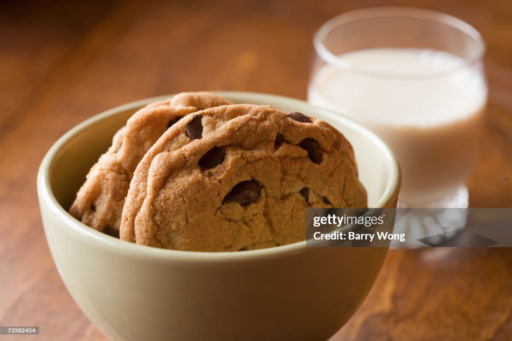 Chocolate chip cookies in bowl, and glass of milk