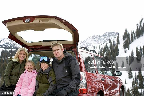 family sitting in back of parked suv on ski trip in mountains, smiling, portrait - suv berg stock-fotos und bilder