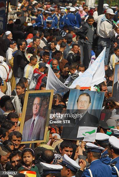 People hold up portraits of Algerian President Abdelaziz Bouteflika and Spanish King Juan Carlos, as they walk on a main street during a public...