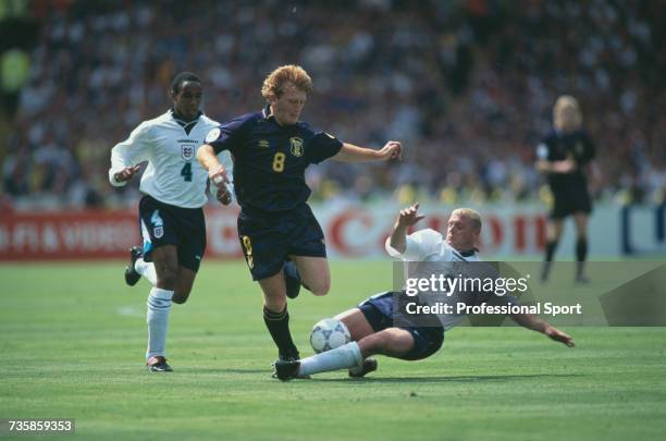 English footballer and midfielder with the England national team, Paul Gascoigne dives to tackle Stuart McCall of Scotland for the ball as fellow...