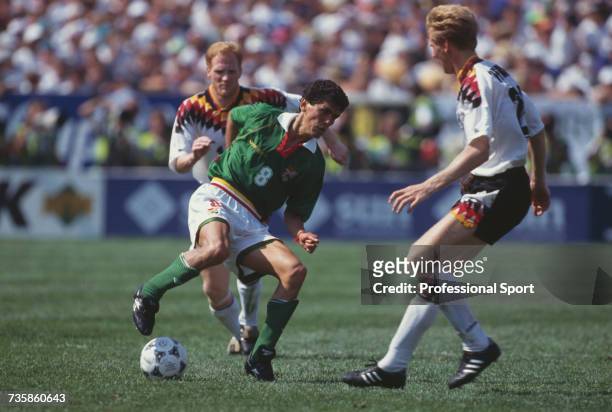 Bolivian footballer Jose Milton Melgar pictured in action with the ball as he attempts to pass German midfielder Stefan Effenberg , with fellow...