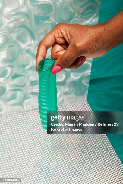 young woman holding unwrapped condom - condon fotografías e imágenes de stock