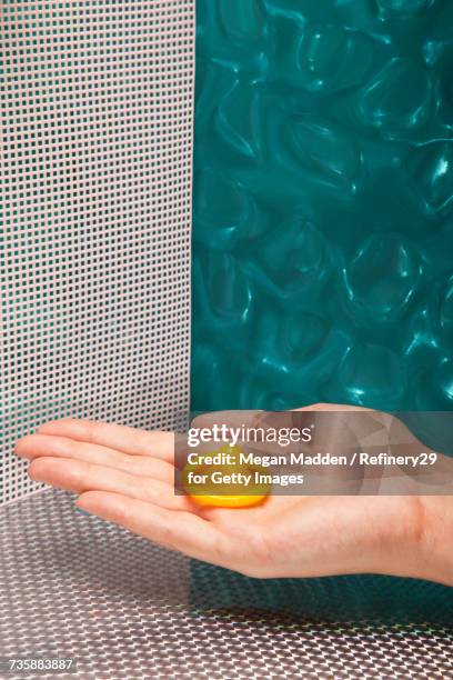 young woman holding unwrapped condom - birth control stockfoto's en -beelden