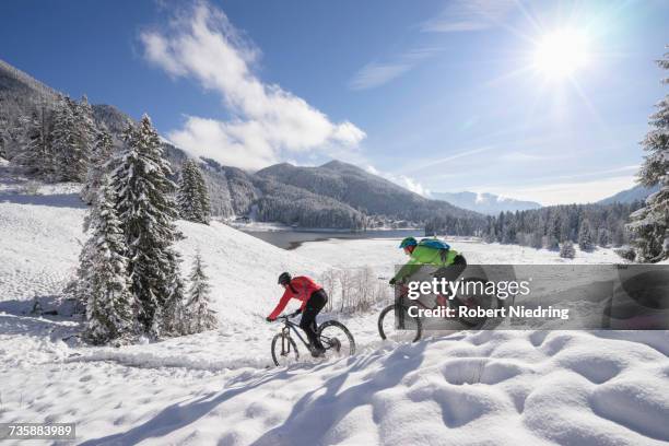 mountain bikers moving down on snowcapped mountain - cross country cycling stock pictures, royalty-free photos & images