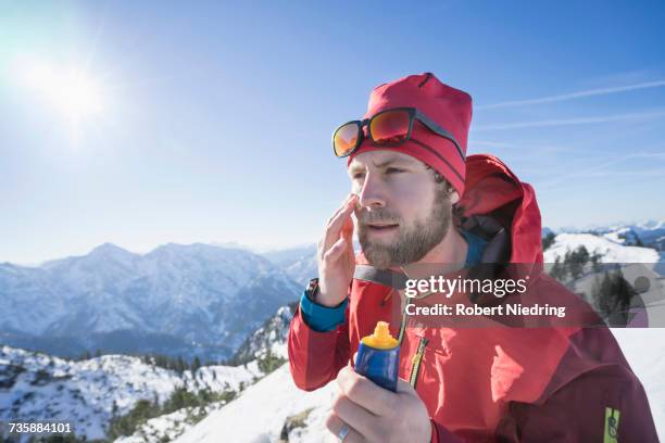 skier applying sun cream on face - mann creme stock-fotos und bilder