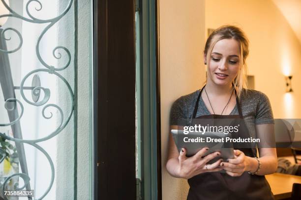 woman wearing apron and using tablet - newtechnology stock pictures, royalty-free photos & images