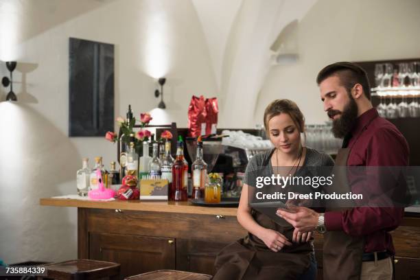 confident restaurant owners discussing while using digital tablet  - newtechnology stock pictures, royalty-free photos & images