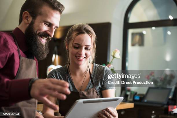 young owners discussion while holding tablet at restaurant - newtechnology stock pictures, royalty-free photos & images