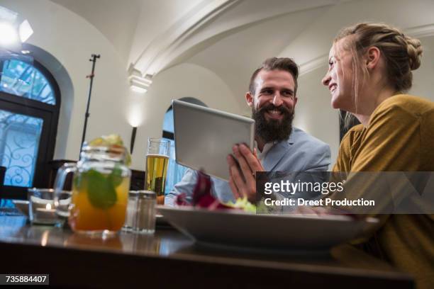 smiling couple using digital tablet at restaurant - newtechnology stockfoto's en -beelden