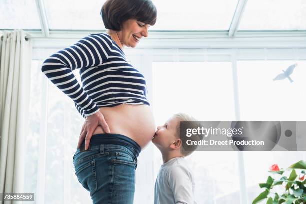 little boy kissing a stomach of pregnant mother at home - belly kissing stock pictures, royalty-free photos & images