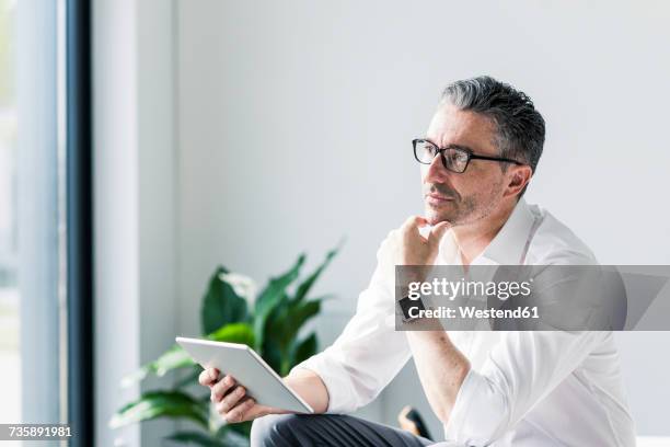 portrait of pensive businessman with tablet and smartwatch - business man on ipad stock-fotos und bilder