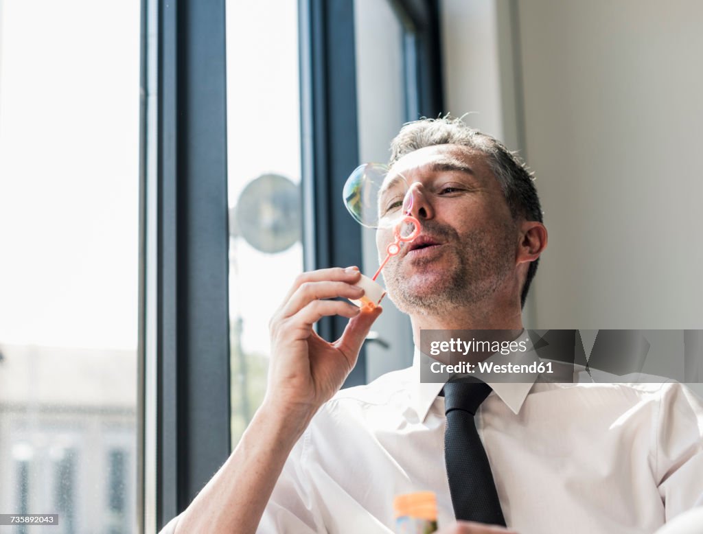 Businessman blowing soap bubbles