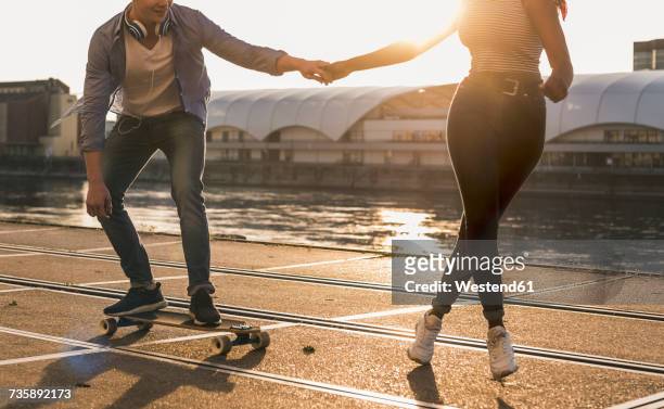 young couple skateboarding at the riverside - freizeit stock-fotos und bilder