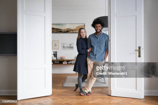 smiling couple at home standing in door frame - couple full length stock pictures, royalty-free photos & images