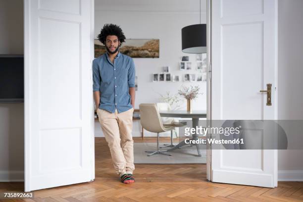 man at home standing in door frame in living room - casual room imagens e fotografias de stock