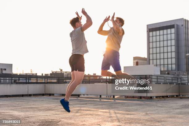 friends playing basketball at sunset on a rooftop - dramatic millennials stock pictures, royalty-free photos & images