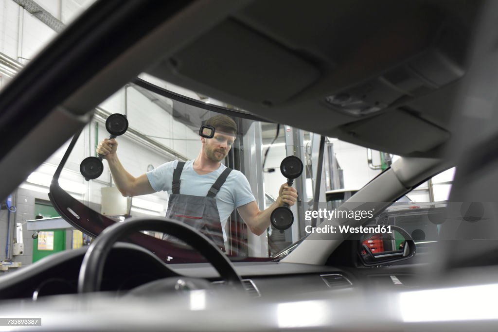 Car mechanic in a workshop changing car window