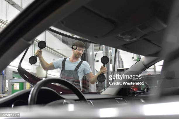 car mechanic in a workshop changing car window - windshield - fotografias e filmes do acervo