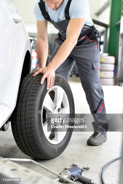 car mechanic in a workshop changing car tyre - flat tyre stock pictures, royalty-free photos & images