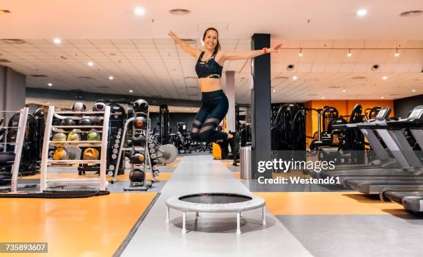 young woman jumping in the gym - trampoline stock-fotos und bilder