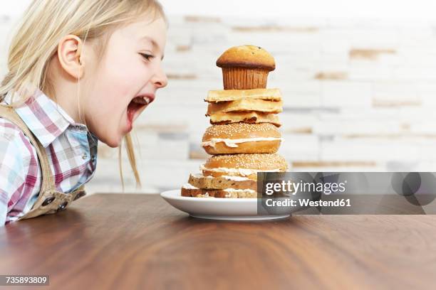 hungry little girl with stack of baked goods - child eat side stock-fotos und bilder