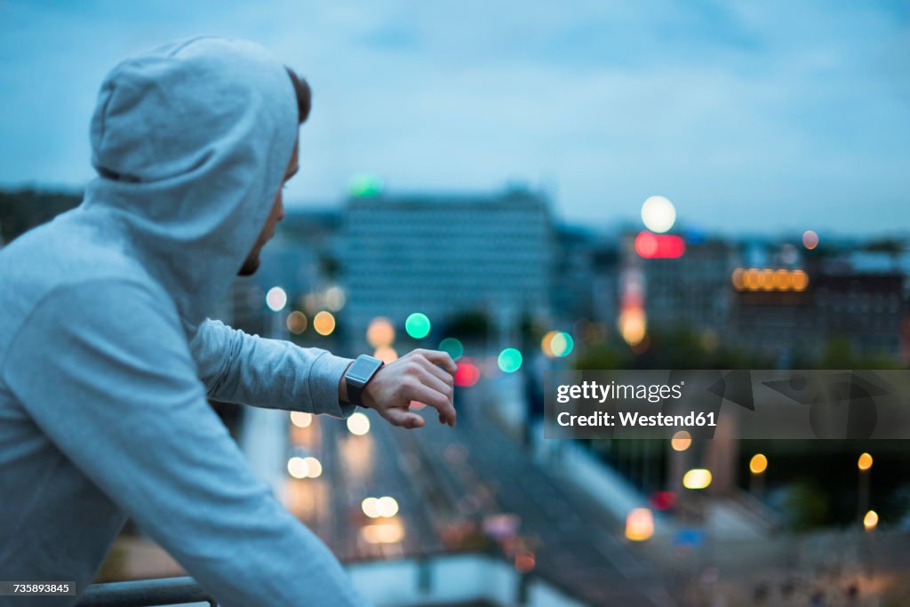 Athlete checking his smartwatch above the city at dawn