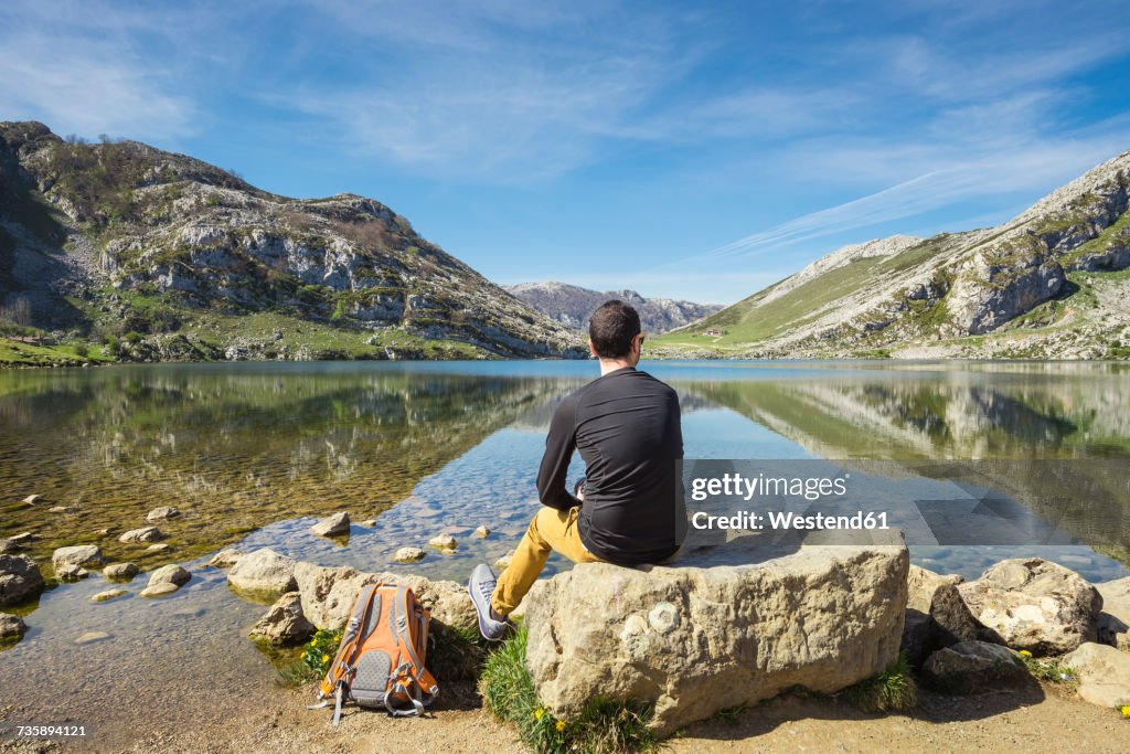 Spain, Asturias, Picos de Europa National Park, man sitting at Lakes of Covadonga