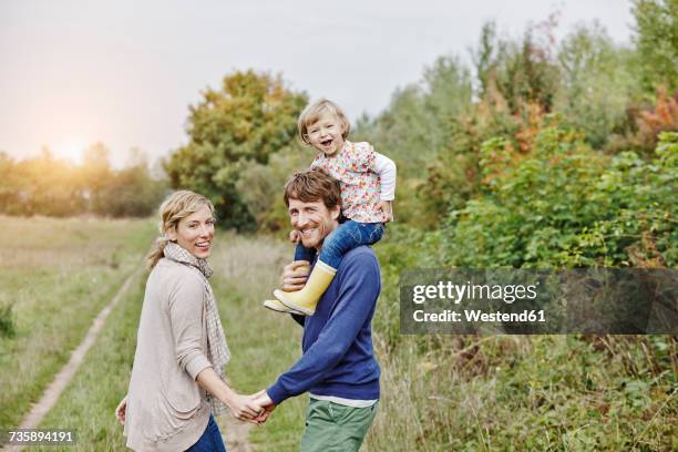 family on a trip with father carrying daughter on shoulders - familie mit einem kind stock-fotos und bilder