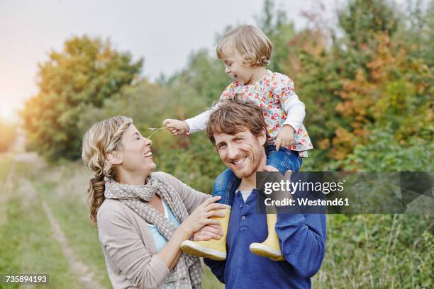 family on a trip with father carrying daughter on shoulders - blades of grass stock-fotos und bilder