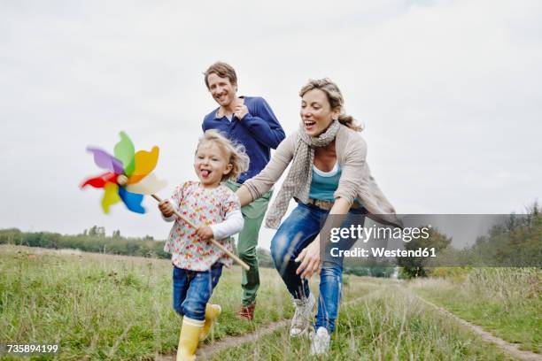 family on a trip with daughter holding pinwheel - jung glücklich natur stock-fotos und bilder