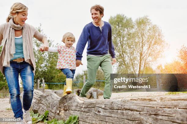 girl balancing on a log supported by parents - balance family stock pictures, royalty-free photos & images