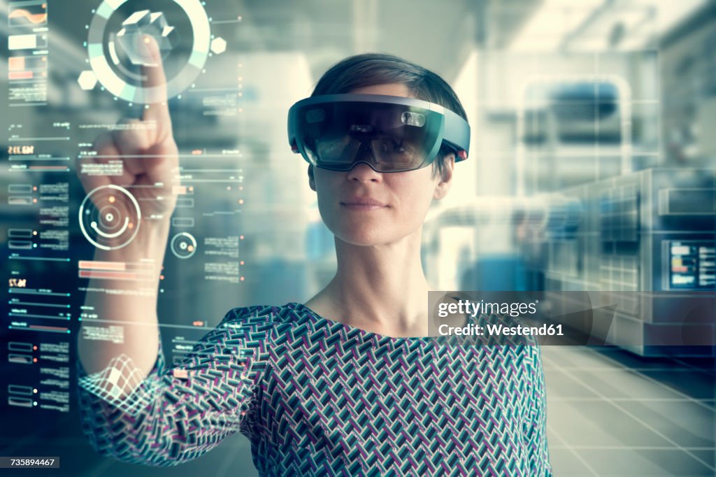 Woman wearing mixed reality smartglasses touching transparent screen