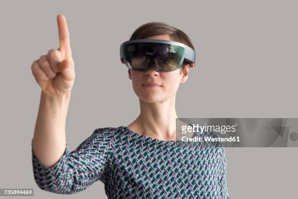 woman wearing mixed reality smartglasses raising her hand - 見えない ストックフォトと画像