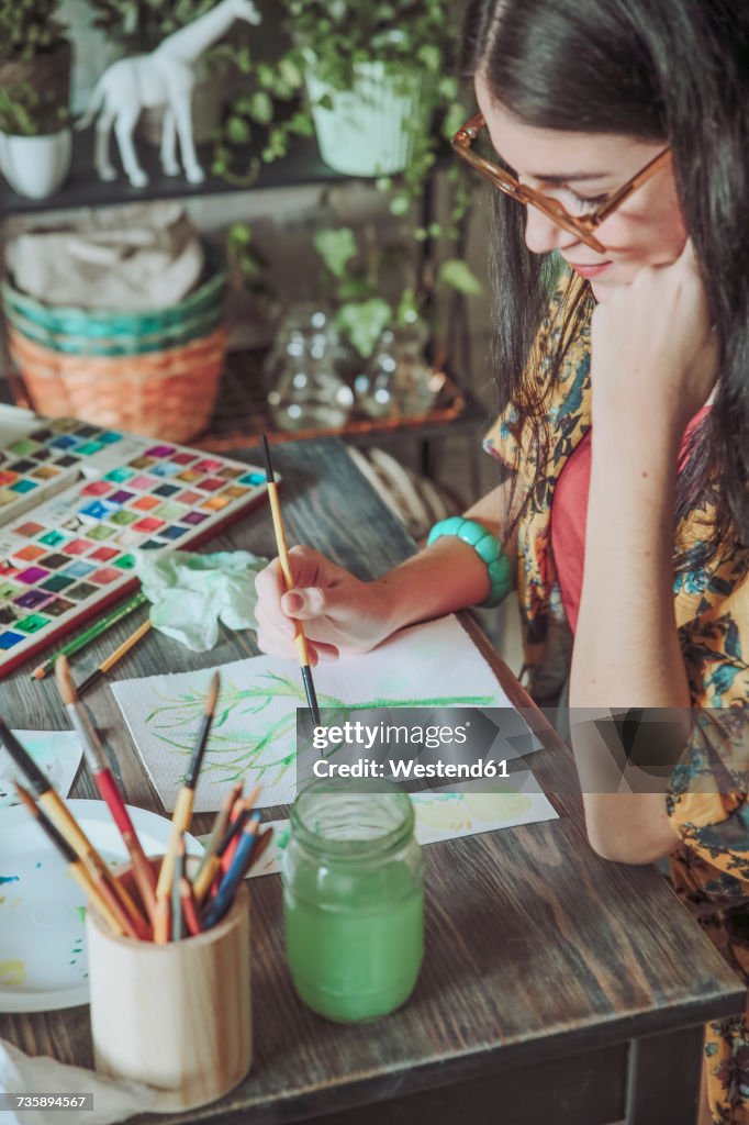 Young woman painting plants with water colors