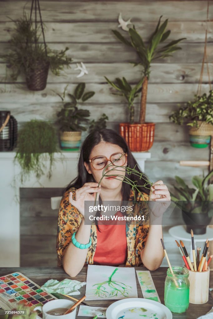 Young woman painting plants with water colors