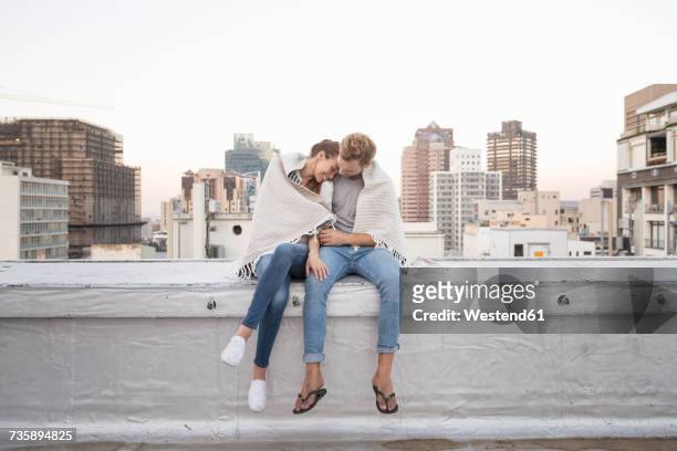 romantic couple sitting on rooftop terrace, enjoying the view - couple in love stock pictures, royalty-free photos & images