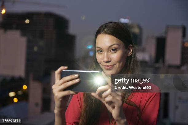 young woman taking pictures of friends at a rooftop party - lampe de poche photos et images de collection