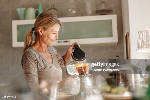 woman at home in kitchen preparing coffee - breakfast woman stockfoto's en -beelden