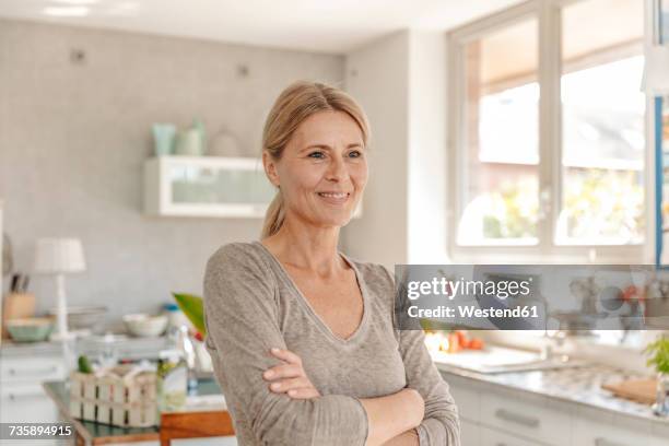 portrait of smiling woman at home in kitchen - stereotypical housewife stock-fotos und bilder