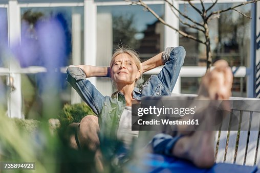 Smiling woman with laptop relaxing on garden bench Smiling woman with laptop relaxing on garden bench