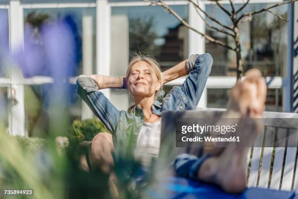 smiling woman with laptop relaxing on garden bench - feet up stock pictures, royalty-free photos & images