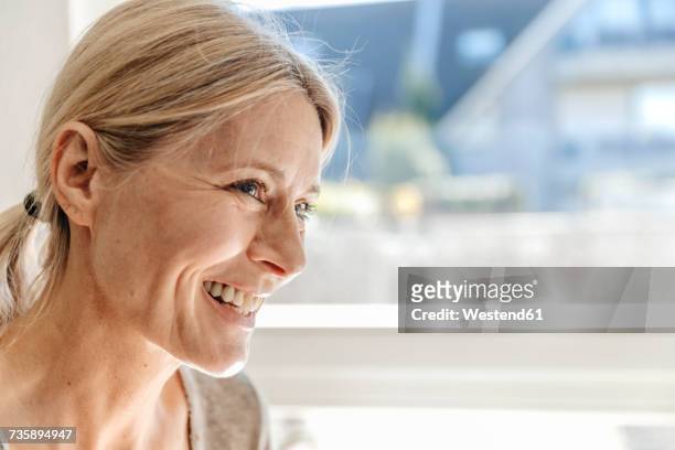 portrait of smiling woman at home - personnes adultes de profil rire photos et images de collection